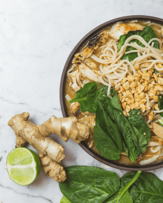 Ingwerknolle neben einer Schüssel Ramen